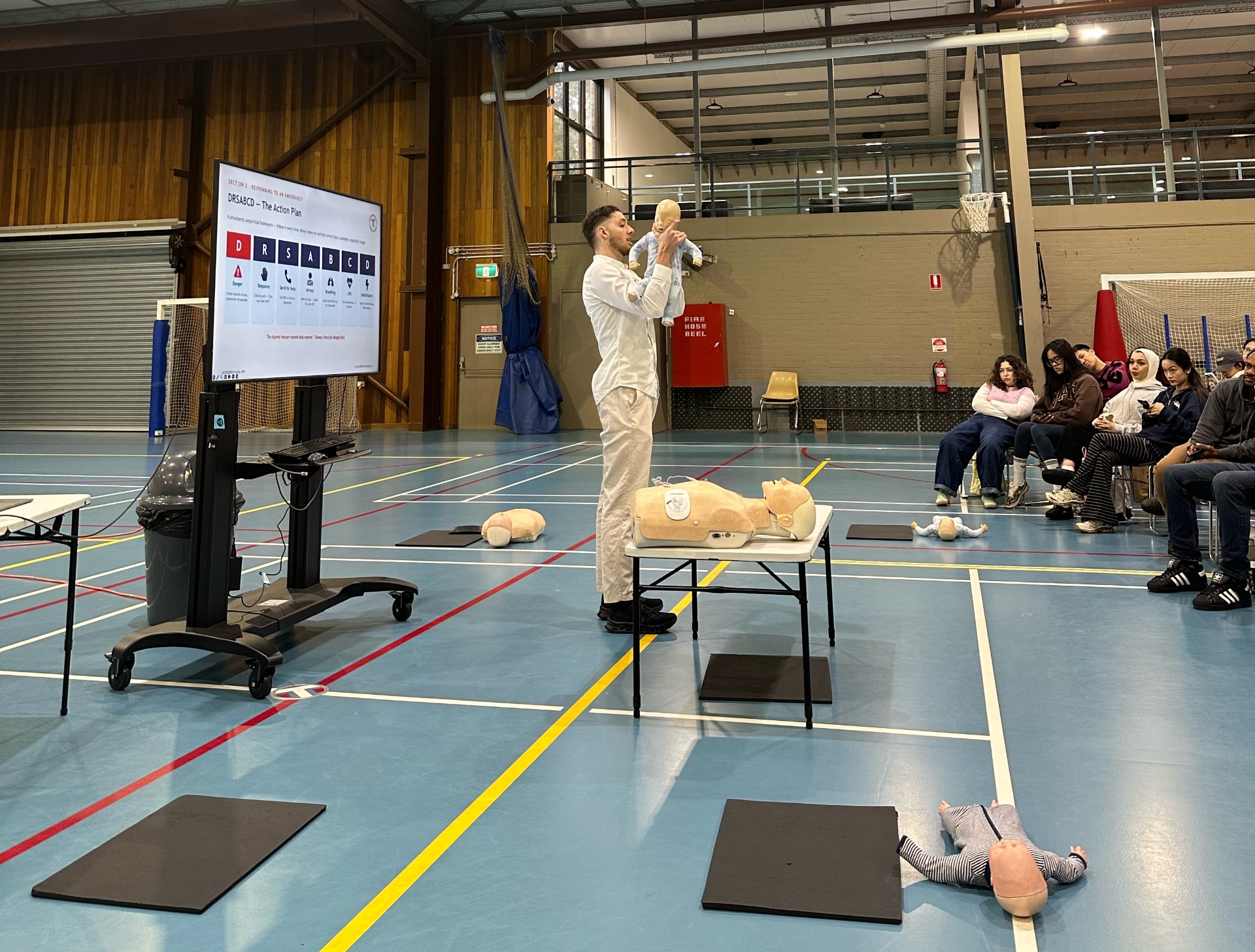Acmea Academy trainer demonstrating first aid techniques with CPR manikins during a practical training session